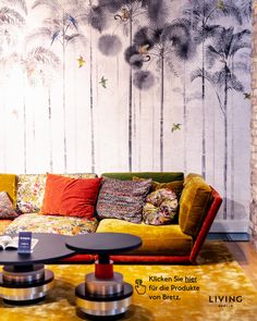 a living room with yellow couches and colorful pillows on the floor, next to a wall mural