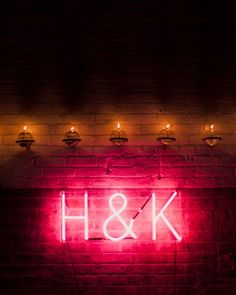 a red neon sign that says h & k on the side of a brick wall