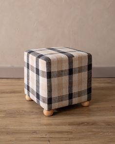 a black and white checkered ottoman sitting on top of a hard wood floor next to a wall