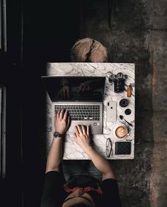 a person sitting at a desk using a laptop computer with their hands on the keyboard