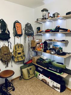 a room filled with lots of backpacks and other items on shelves next to a chair