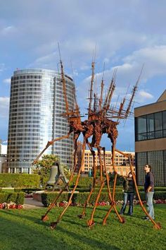 two people standing in front of a large metal sculpture on top of a green field