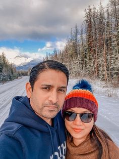 a man and woman taking a selfie on a snowy road in the wintertime