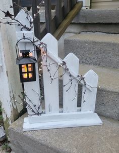 a lantern is on top of a white picket fence