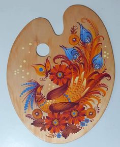 a wooden cutting board decorated with colorful flowers and birds on it's side, sitting on a white surface