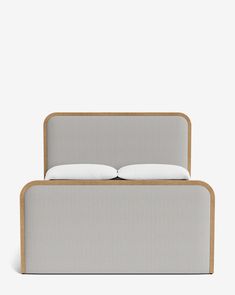 a bed with two pillows on top of it and a wooden frame around the headboard