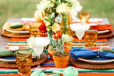 the table is set with colorful plates and flowers