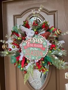 a christmas wreath with the words jesus is the reason and season hanging on a door