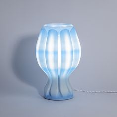 a blue vase sitting on top of a table next to a white corded light