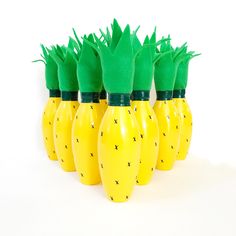 a group of yellow vases with green tops and black crosses painted on them, lined up against a white background