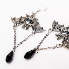 Unleash your inner darkness with these captivating Bat Earrings. Crafted from durable zinc alloy with a striking black finish, each earring measures 1.5 by 1 inch, featuring an elegant 1-inch chain adorned with a black diamond-shaped accent. Perfect for adding a touch of gothic charm to any outfit, these earrings are a must-have for your collection. Silver Alloy Jewelry For Evening, Punk Alloy Jewelry For Halloween, Pierced Alloy Jewelry For Party, Alloy Drop Earrings For Party, Silver Alloy Crystal Earrings, Nickel-free Alloy Earrings For Party, Black Alloy Halloween Jewelry, Edgy Jewelry For Halloween Gift, Black Alloy Jewelry For Halloween