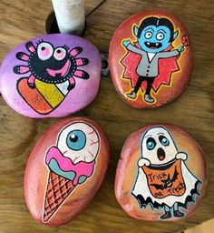 four painted rocks sitting on top of a wooden table