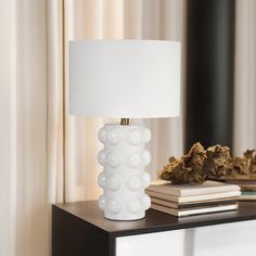 a white lamp sitting on top of a table next to a book