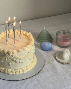 a birthday cake with candles on it sitting on a table next to seashells