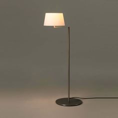 a floor lamp with a white shade on it's side and a black base