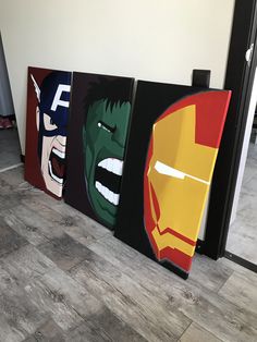 four paintings of superheros are displayed on the wall next to each other in an office