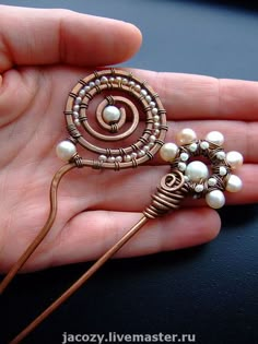 a person is holding a brooch with pearls on it's back and in the palm of their hand