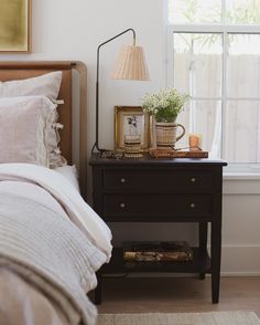 a bedroom with a bed, nightstand and pictures on the side table next to it