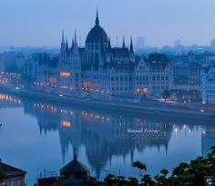 the city is lit up at night by the river