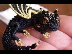 a tiny black and gold dragon figurine sitting on top of a persons finger