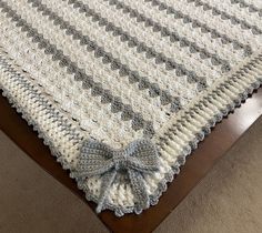 a crocheted blanket with a bow on the edge and a wooden bed frame