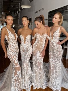 three beautiful women standing next to each other wearing dresses with white flowers on the side