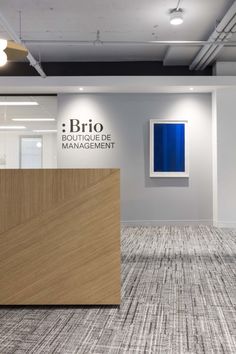 an empty office with wooden reception desks and blue art on the wall behind it