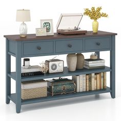 a blue table with books, pictures and a laptop on it's shelf next to a lamp