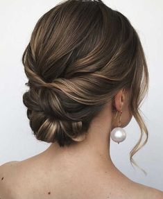 a woman with her hair in a low updo and pearls on the back of her head