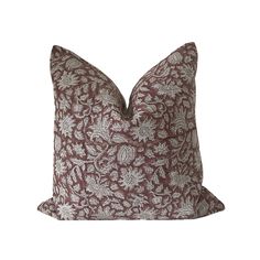 a brown and white floral pillow on a white background