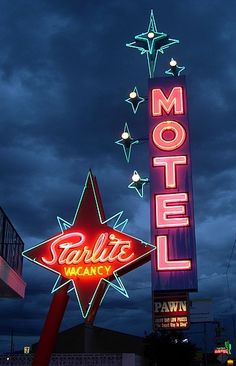 the neon sign is lit up in front of the motel at night with stars on it