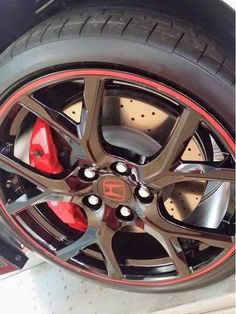 the front wheel of a sports car with red brake pads and black rims on it