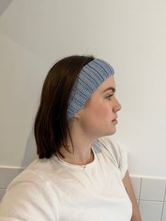 a woman wearing a blue headband sitting in front of a white tiled bathroom wall