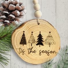 a wooden ornament with the words tis the season on it next to pine cones