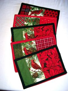 four placemats with red and green designs on them sitting on a white table