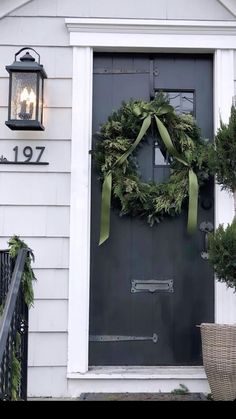 a wreath on the front door of a house with green ribbon hanging from it's side