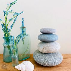 two vases filled with flowers and rocks next to each other on a wooden table