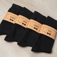 three pairs of black socks with brown labels on them