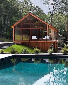 a house that is next to a pool in the grass and some trees around it