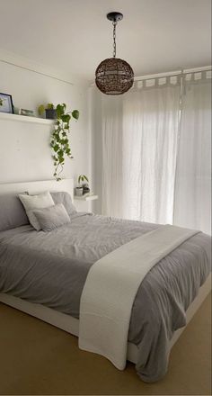 a bedroom with a large bed and hanging plant on the wall next to the window