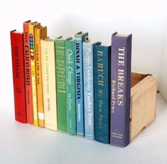 a row of colorful books sitting on top of a wooden box next to each other