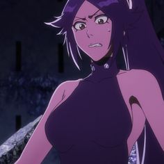 a woman with purple hair is standing in front of some rocks and looking at the camera