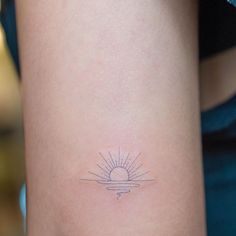 a small sun tattoo on the back of a woman's arm