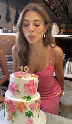 a woman blowing out the candles on her birthday cake while standing in front of a counter