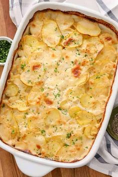 a casserole dish with potatoes and parsley in it on a wooden table