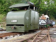 two men are riding in the caboose of an old green train on railroad tracks