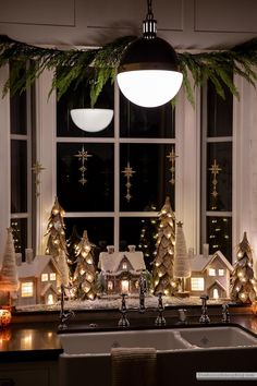 a kitchen with christmas decorations and lights on the window sill, next to a sink