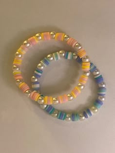 two bracelets with multicolored beads on white surface