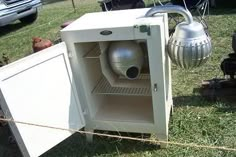 an open refrigerator sitting on top of a grass covered field next to a fire hydrant