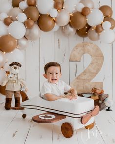 a young boy is sitting in a toy boat with balloons around him and the number two on it